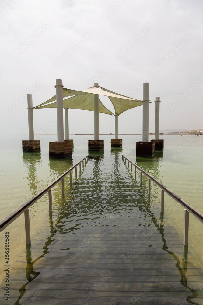 Fototapeta premium Path leading into the water on a sandy beach at the Dead Sea during a sunny day. Taken in Ein Bokek, Israel.