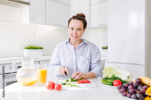 Young mother prepares Breakfast for the family sitting at the table in the kitchen