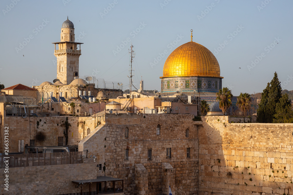 View of the Dome of the Rock and the Western Wall in the Old City during a sunny evening before sunset. Taken in Jerusalem, Israel.