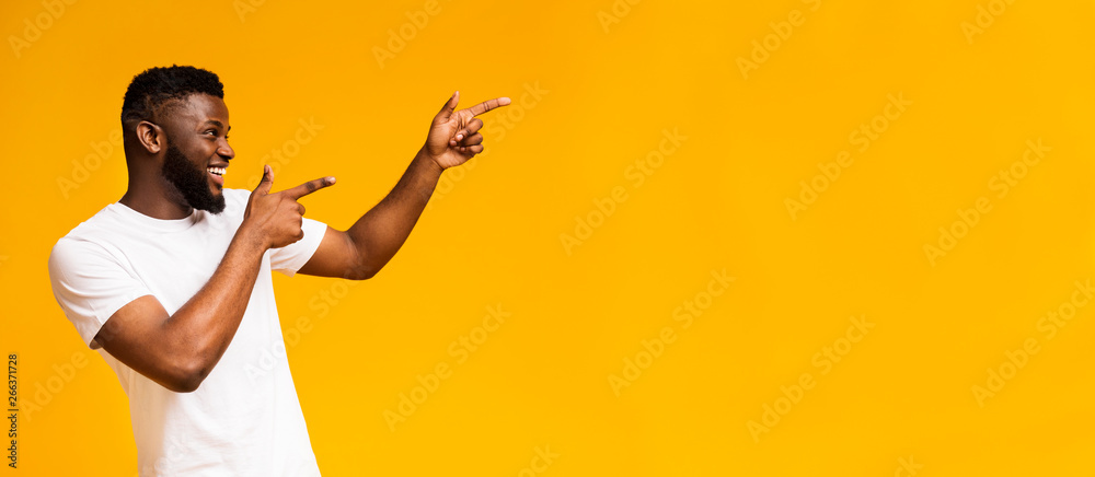 © Prostock-studio - Positive african american guy pointing aside at free space