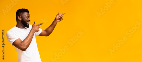 Positive african american guy pointing aside at free space photo
