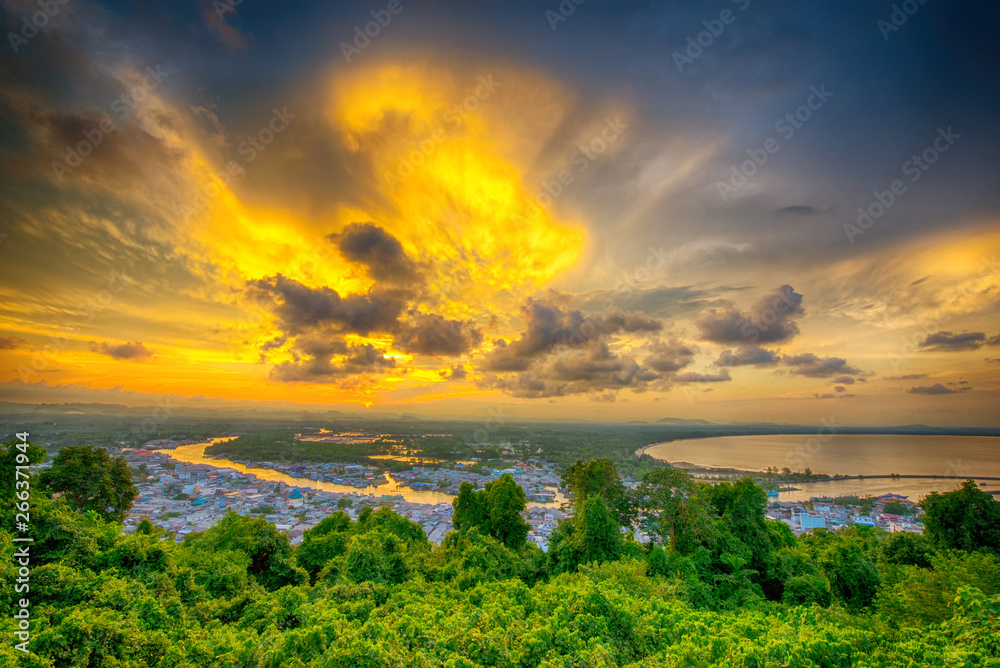 Clouds of beautiful color in the summer sunset, Dark Clouds, Natural beautiful cloudscape over the sea with sunlight background and green forest in the foreground at Ban Pak Nam, Chumphon, Thailand.