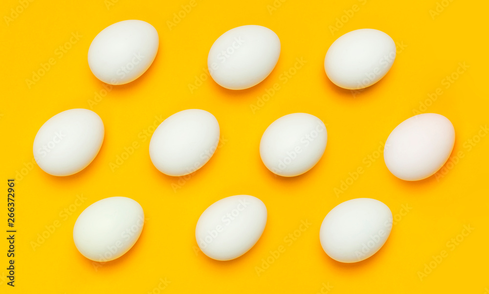 Pattern from White chicken eggs on yellow background top view flat lay copy space. Creative food minimalistic background, Easter. Natural healthy food and organic farming concept.