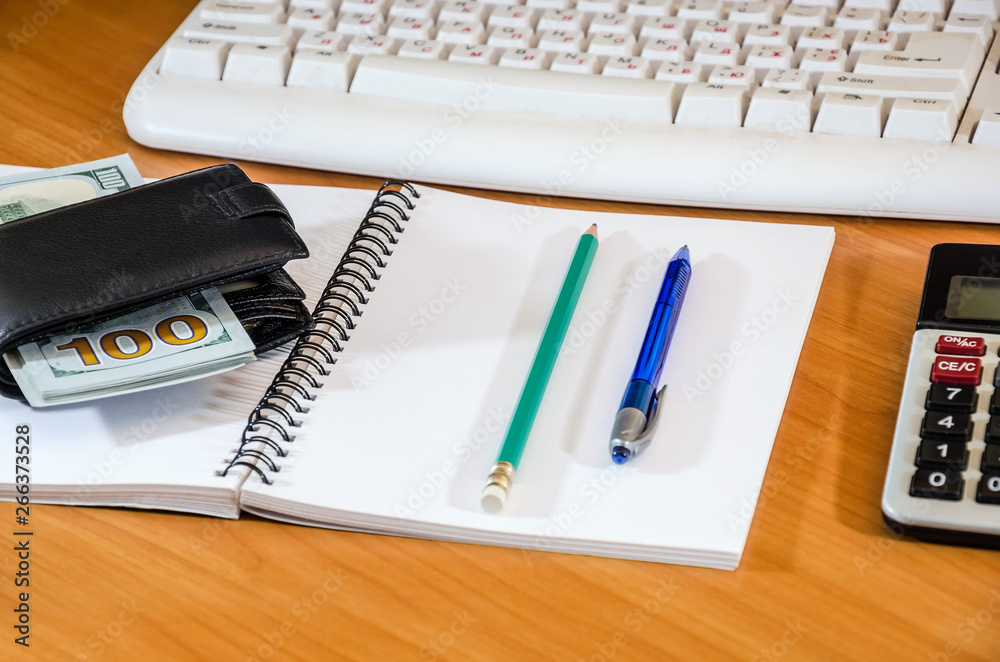 Notebook with pen and pencil, dollars, keyboard on the table Notebook with pen and pencil, dollars, keyboard on the table