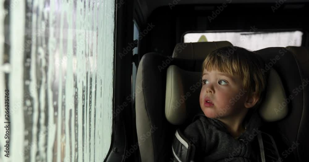 Little boy looking through misted window. Cleaning Car Using High Pressure Water. Car wash, car wash foam water. From inside the car.