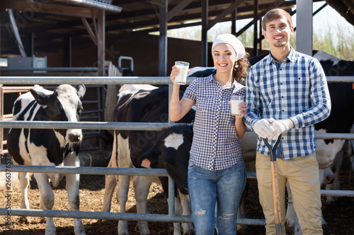 Portrait of two farm workers holding glass with milk