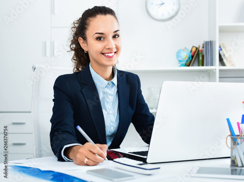 Business lady sitting at office desk with laptop photo