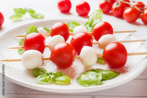 Caprese salad of tomatoes, mozzarella cheese and Basil on a white plate. Italian cuisine.
