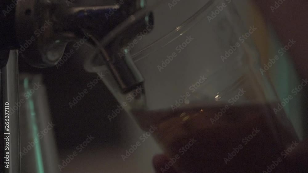 Close up of a person pulling a pint of beer into a plastic pint glass Close up of a person pulling a pint of beer into a plastic pint glass