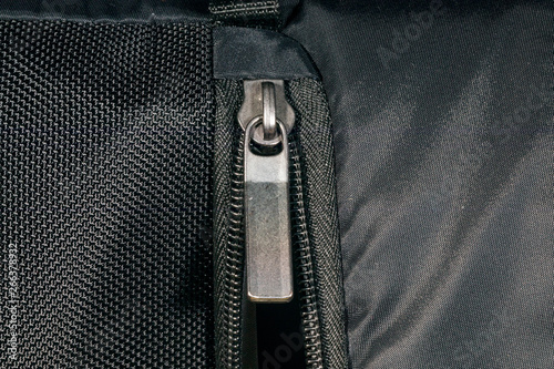 Zipper made of metal on a black backpack. Close-up view