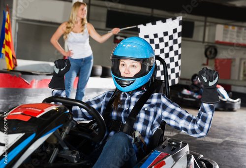 woman driving sport car and woman with race flag on background