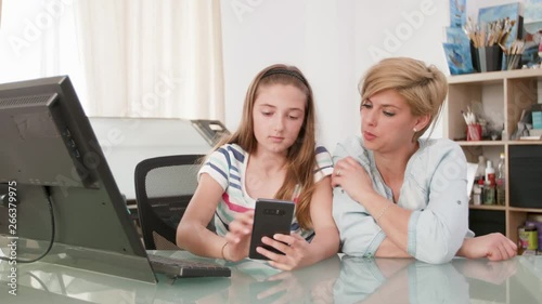 Young teenage girl showing something to her mother on a smartphone. Mom and teenage daughter looking at a smartphone screen.