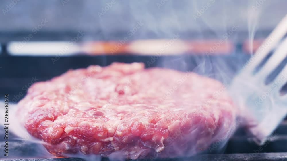 Chef puts a delicious piece of meat on the grill. Tasty meat for a burger cooked on a fiery barbecue grill. Close up of chief cooked very satisfying protein tasty burger in casual bar Chef puts a delicious piece of meat on the grill. Tasty meat for a burger cooked on a fiery barbecue grill. Close up of chief cooked very satisfying protein tasty burger in casual bar