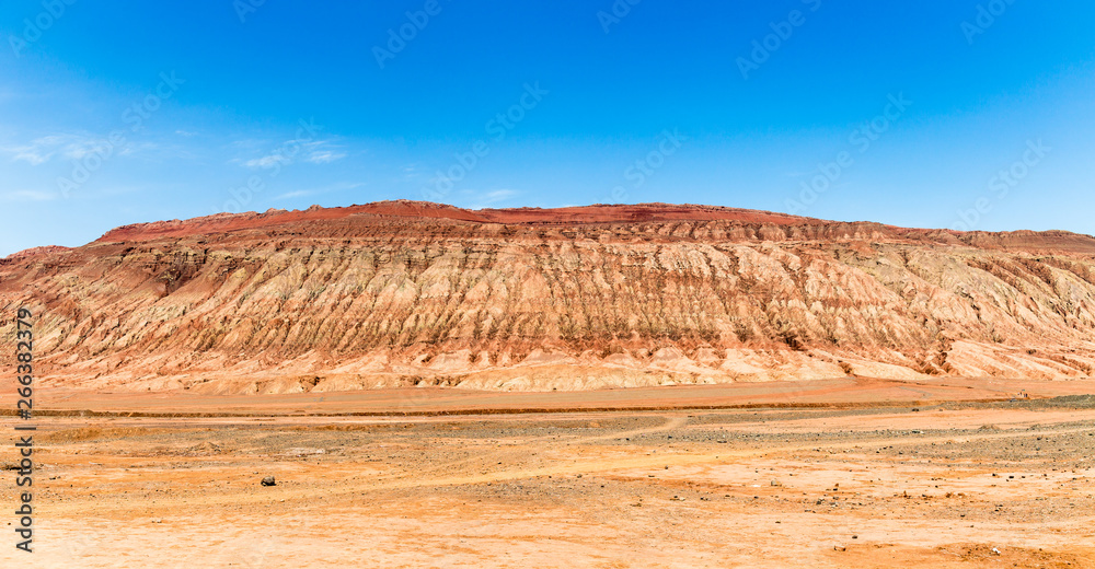 Fototapeta premium Flaming mountains, Turpan, Xinjiang, China: these intense red arid mountains similar to scorching flames appear in the Chinese epic “Journey to the west”. Turpan is an ancient oasis on the Silk Road