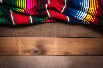 A mexican serape blanket on a wooden plank background