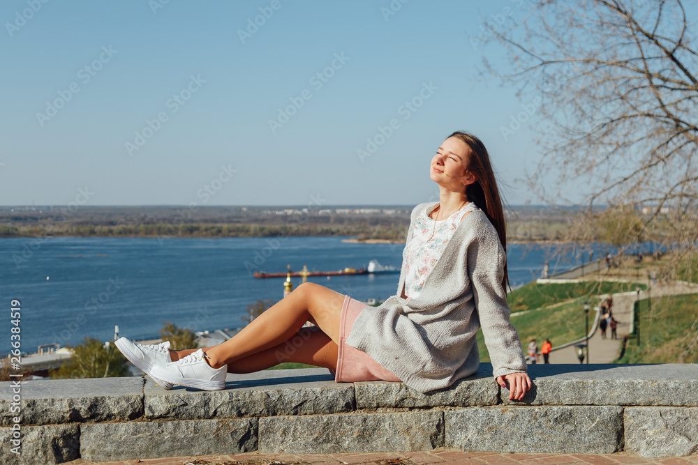 Beautiful young girl sitting on the Volga river embankment