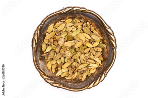 Lot of whole true cardamom pod in old iron bowl flatlay isolated on white background photo