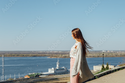 A young girl on the embankment of a Large river, looking at the water.