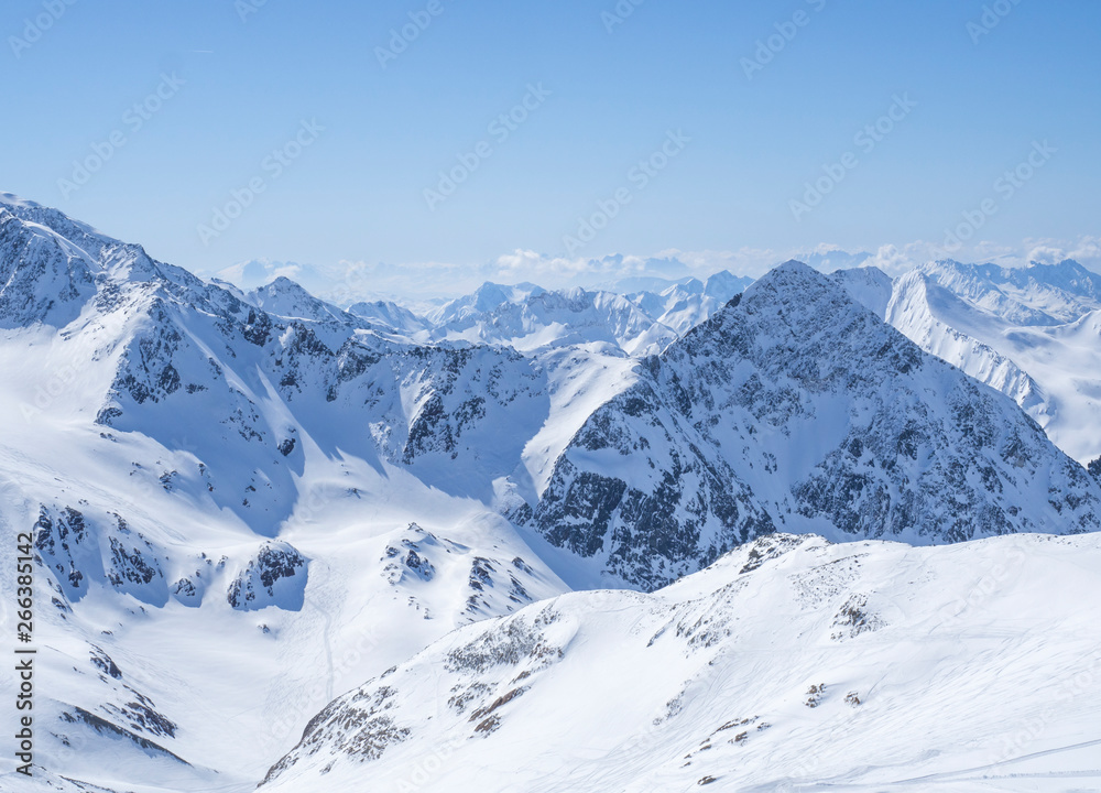 View on winter landscape from the top of Schaufelspitze mountain at Stubai Gletscher ski area with snow covered peaks at spring sunny day. Blue sky background. Stubaital, Tyrol, Austrian Alps