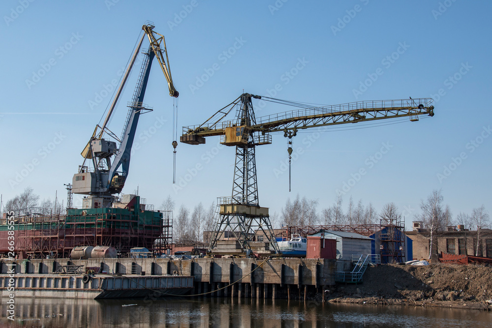 Large spacious dry-cargo barge with cranes on the blue sky background