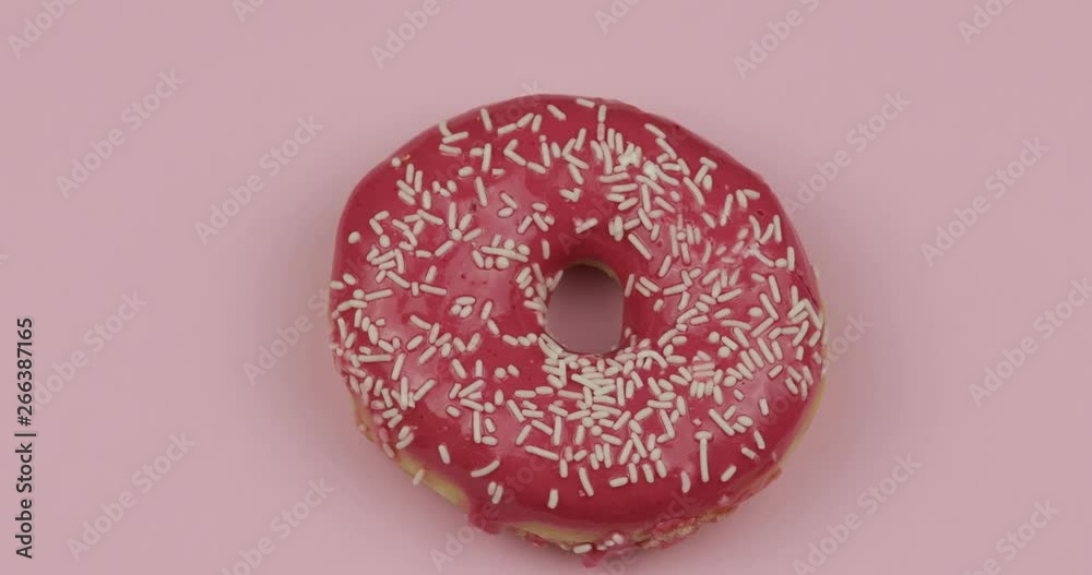Sweet donut rotating on pink background. Top view. Tasty, fresh sprinkled donut Sweet donut rotating on pink background. Top view. Tasty, fresh sprinkled donut