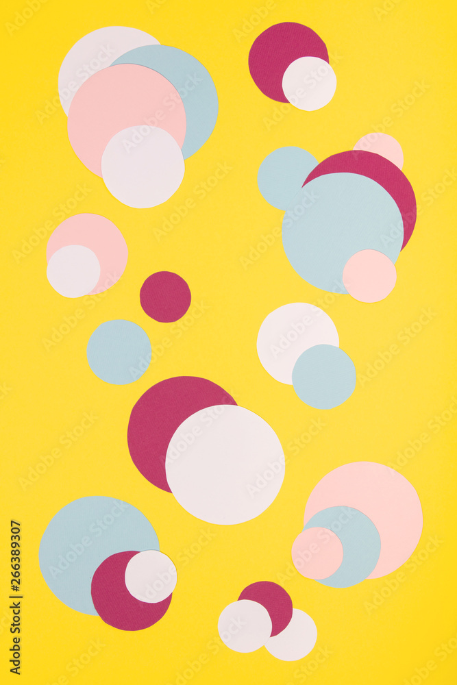 Colorful paper circles on yellow paper background Colorful paper circles on yellow paper background