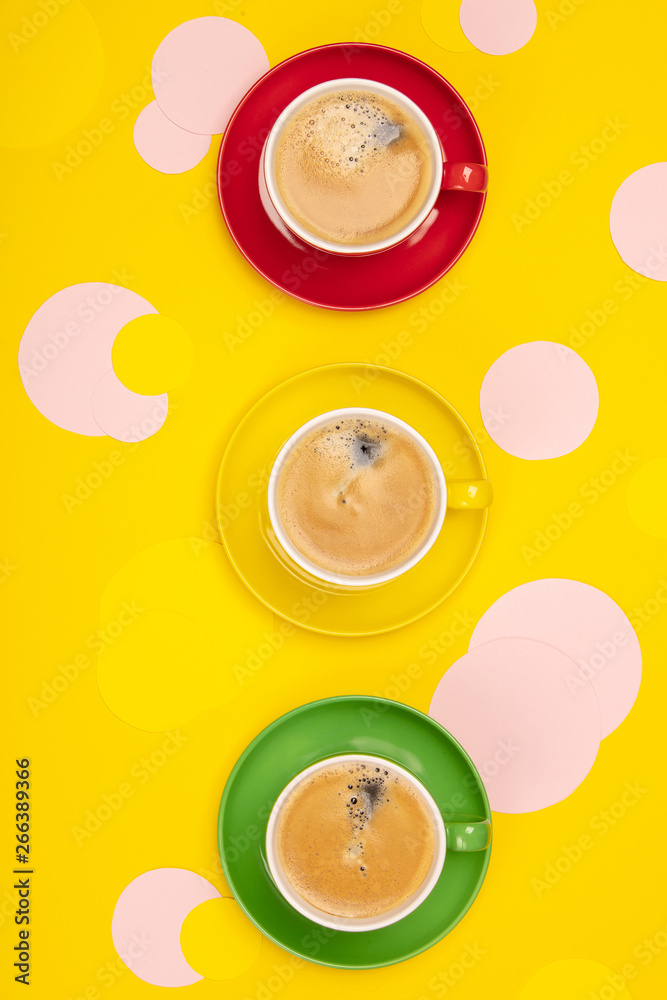 Cups of Coffee and colorful paper circles on yellow paper backgr