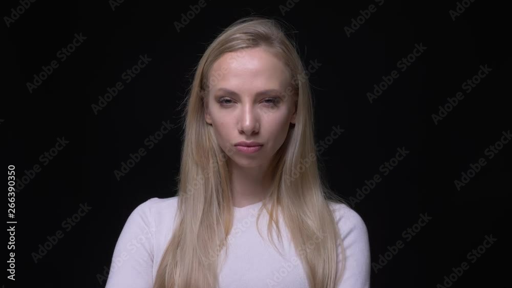 Closeup portrait of young cute pretty blonde female looking and posing in front of the camera with background isolated on black Closeup portrait of young cute pretty blonde female looking and posing in front of the camera with background isolated on black