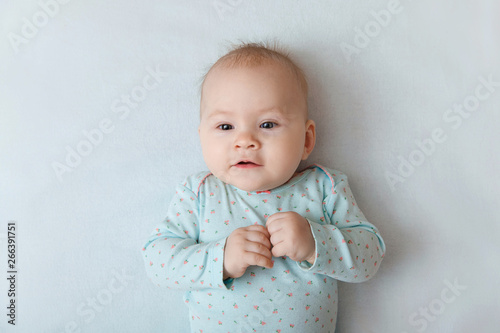 Portrait of a smiling baby in bed. Baby smiling and looking up to camera. Good morning!