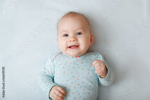 Portrait of a smiling baby in bed. Baby smiling and looking up to camera. Good morning!