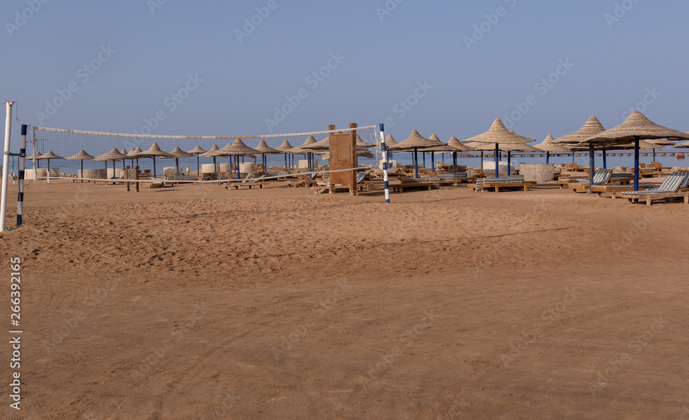 deserted , abandoned beach with sunbeds, umbrellas and a volleyball net overlooking the sea deserted , abandoned beach with sunbeds, umbrellas and a volleyball net overlooking the sea