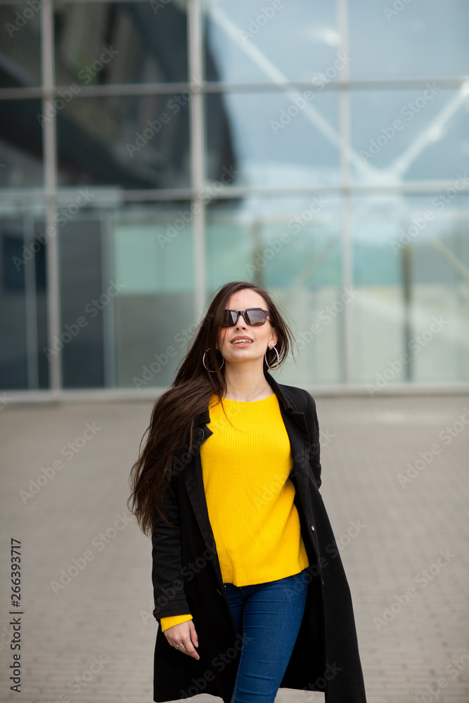 Portrait of a beautiful fashionable stylish woman in bright yellow sweater. Street style shooting