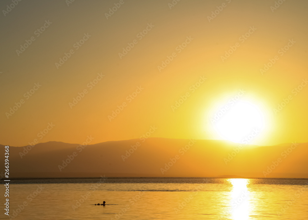 Tourist floating on the Dead Sea during bright sunrise Tourist floating on the Dead Sea during bright sunrise