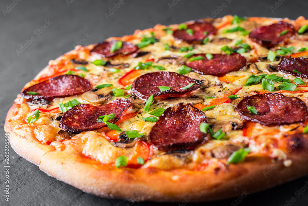 Pepperoni Pizza with Mozzarella cheese, salami, pepper, Spices and mushrooms. Italian pizza on Dark grey black slate background