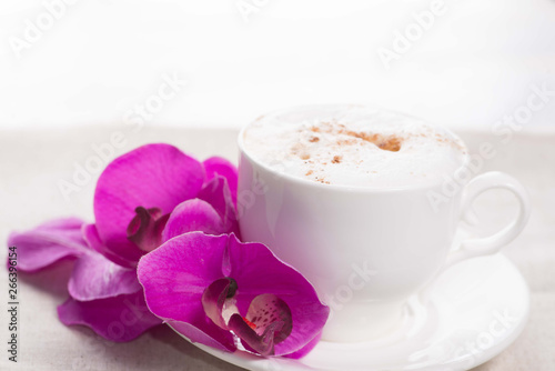white cup of coffee on a background of scattered flower buds on a white background