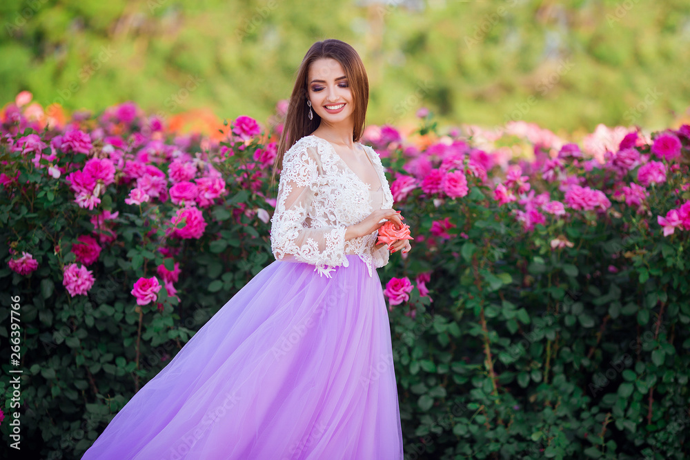 Beautiful girl wearing elegant dress posing near colorful flowers. Art work of romantic woman .