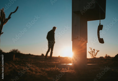 Silhouetted man by a phone booth