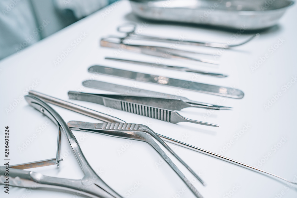 Several surgical instruments lie on a white table Several surgical instruments lie on a white table