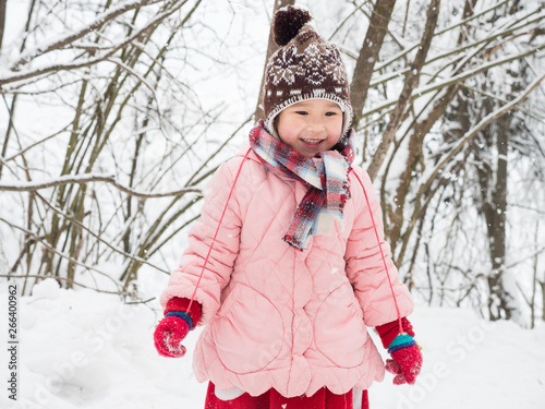 Happy little Chinese girl playing in the snow woods photo