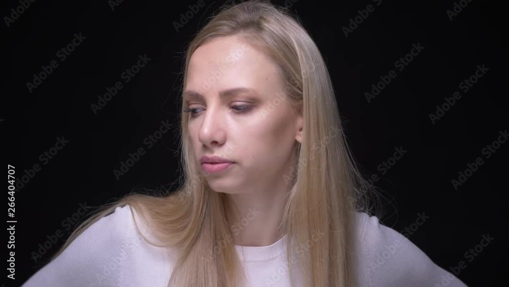 Closeup portrait of young pretty blonde female being angry and frustrated looking at camera with background isolated on black Closeup portrait of young pretty blonde female being angry and frustrated looking at camera with background isolated on black