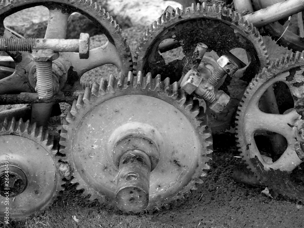 monochrome image of old rusting cogwheels with broken teeth and bolts