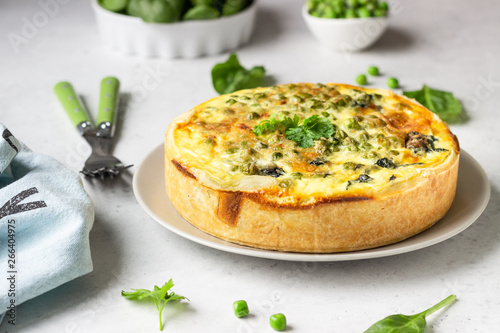 Spinach and green pea quiche, tart or pie with fresh ingredients for baking. Light grey background, copy space.  photo