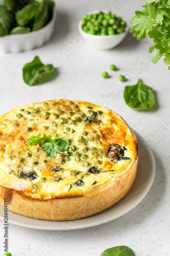 Spinach and green pea quiche, tart or pie with fresh ingredients for baking. Light grey background, copy space. 