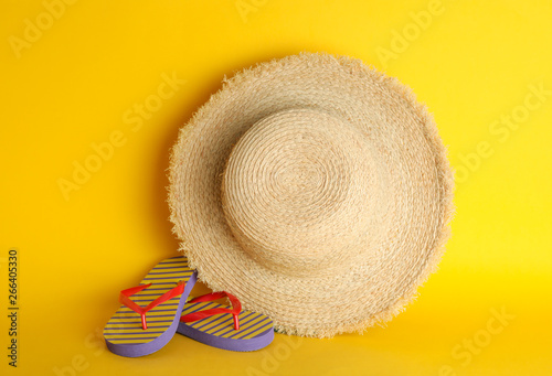 Straw hat and flip flops on color background, space for text. Summer accessories