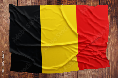 Flag of Belgium on a wooden table background. Wrinkled Belgian flag top view.