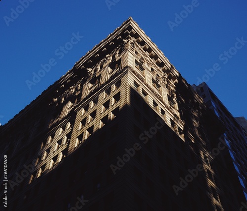 a low angle view of a city building with sharp, contrasting shadows on it's sides