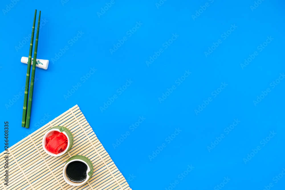 oriental table set up with bamboo sticks for sushi and maki, soy sauce on blue background top view space for text oriental table set up with bamboo sticks for sushi and maki, soy sauce on blue background top view space for text