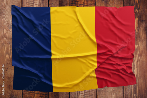 Flag of Chad on a wooden table background. Wrinkled Chadian flag top view.