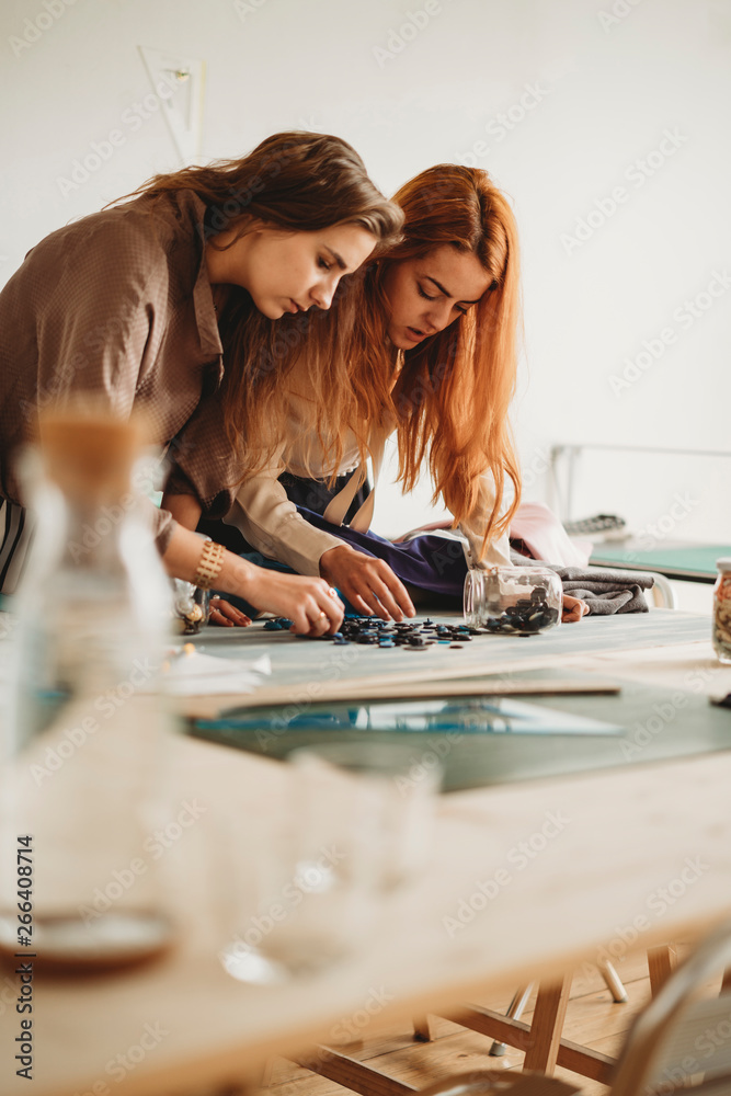 Two female fashion designers looking for buttons Two female fashion designers looking for buttons