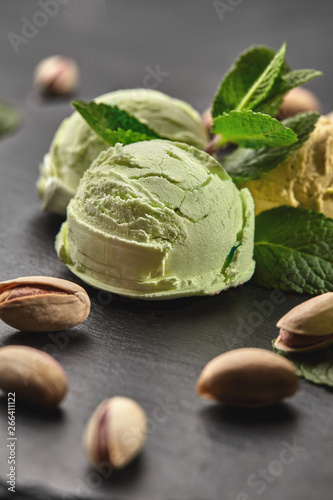 Gourmet pistachio ice cream served on a stone slate over a black background.